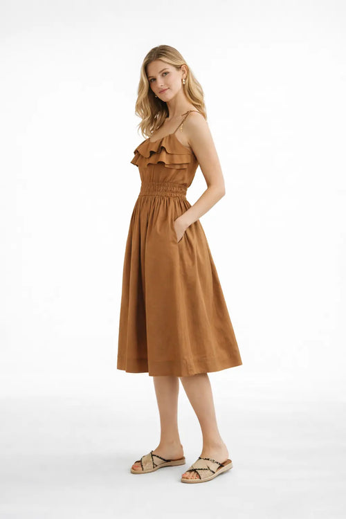 Woman wearing a brown dress with ruffled details on a white background