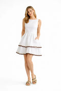 Woman wearing a white dress with brown trim on a white background