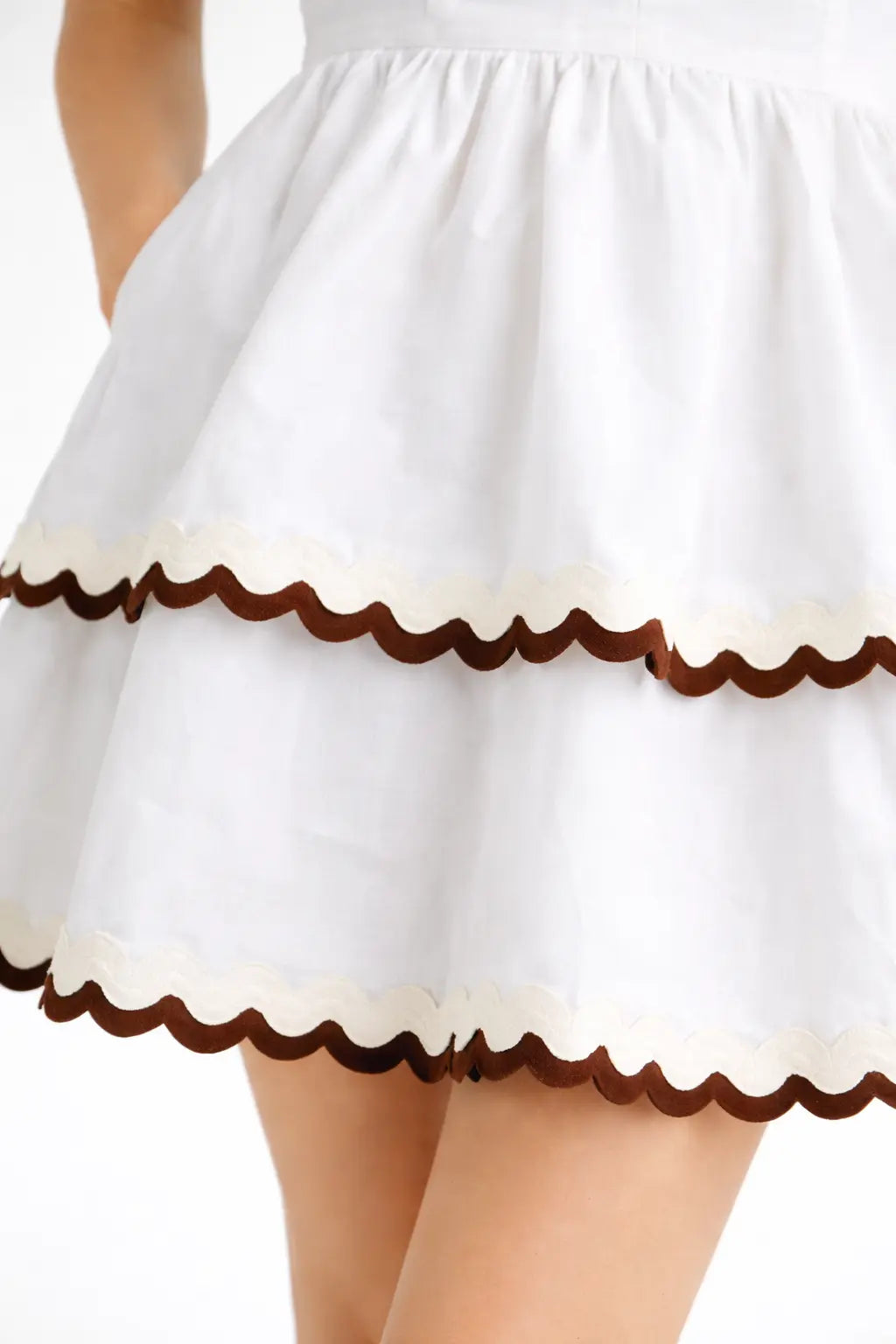 White skirt with brown scalloped edge on a plain background